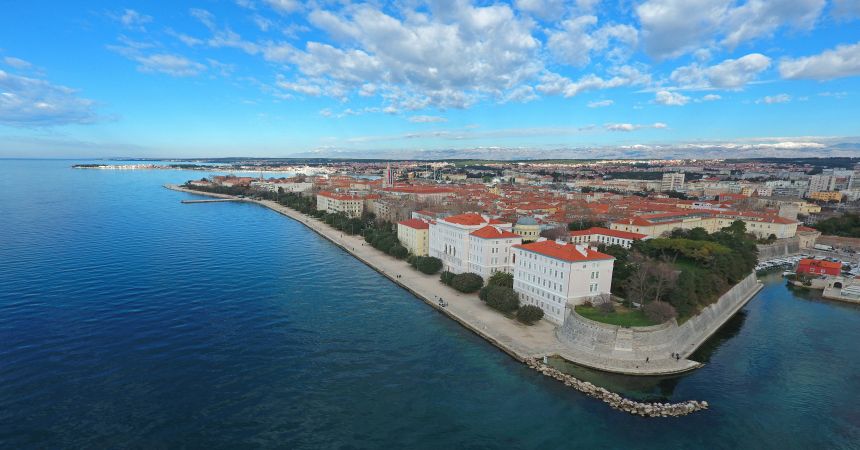 An image of the University of Zadar's main buildings next to the coast, with the city of Zadar behind